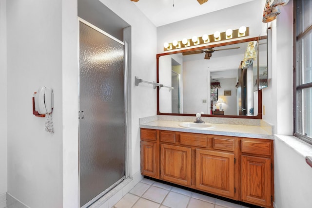 ensuite bathroom with ceiling fan, a shower stall, tile patterned flooring, and vanity