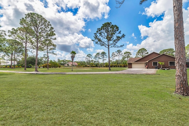 view of grassy yard featuring a garage and driveway