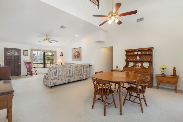 dining space featuring a ceiling fan, light colored carpet, and high vaulted ceiling