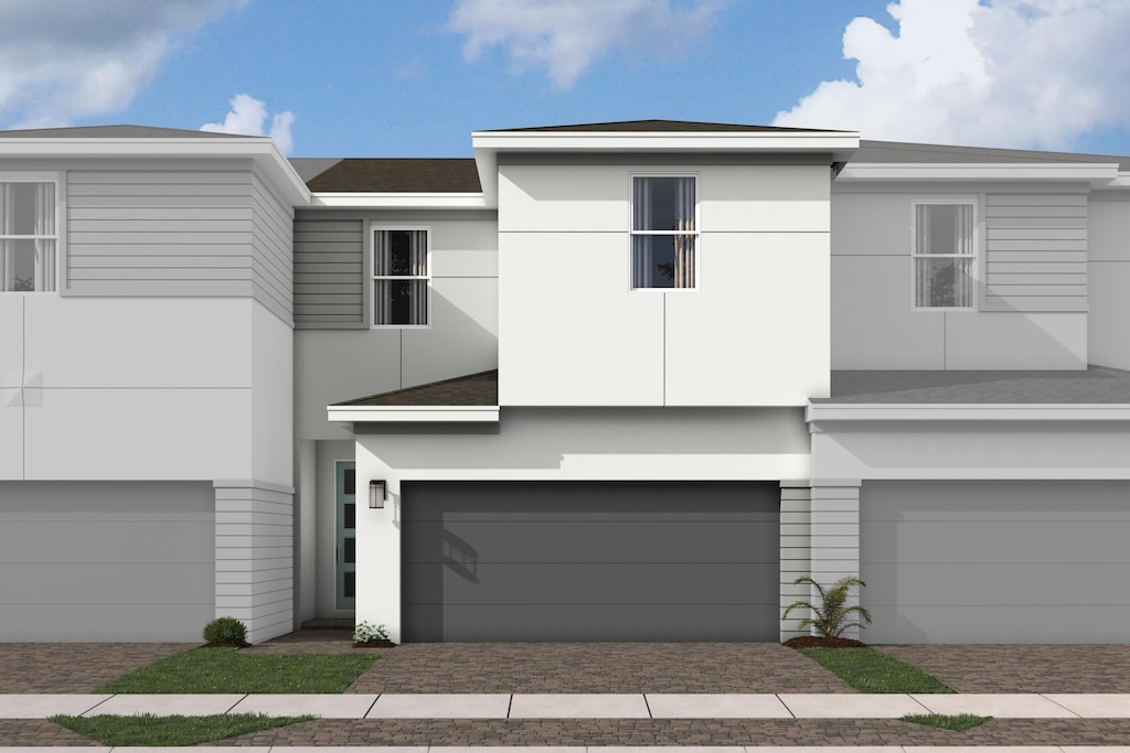 view of front of house with an attached garage, stucco siding, roof with shingles, and driveway