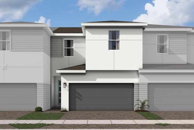 view of front of house with an attached garage, stucco siding, roof with shingles, and driveway