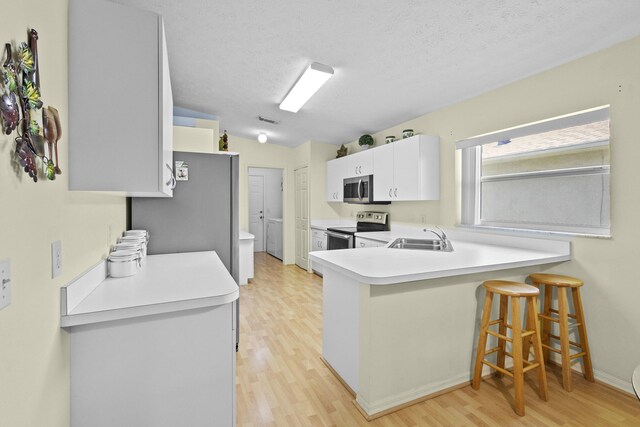 6527 Alheli, Fort Pierce, FL 34951 - kitchen with appliances with stainless steel finishes, light wood-style floors, a kitchen bar, a peninsula, and light countertops