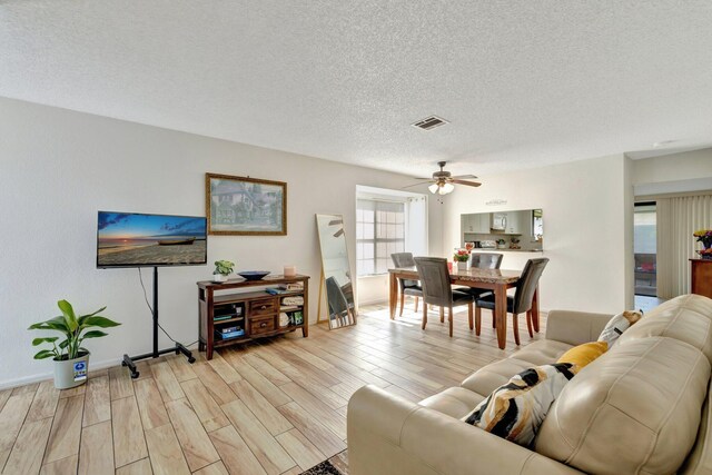 555 SW Sara Blvd, Port Saint Lucie, FL 34953 - living room featuring light wood-type flooring, a ceiling fan, a textured ceiling, and baseboards