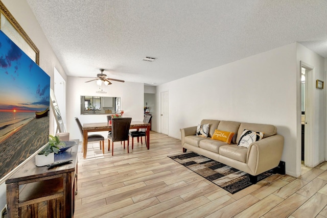 555 SW Sara Blvd, Port Saint Lucie, FL 34953 - living area featuring light wood finished floors, a textured ceiling, and a ceiling fan