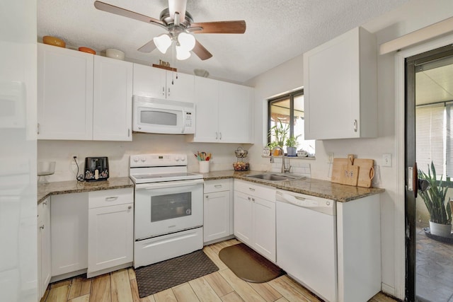 555 SW Sara Blvd, Port Saint Lucie, FL 34953 - kitchen with white appliances, a sink, white cabinets, a ceiling fan, and light stone countertops