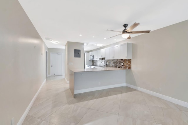 1131 Violet Ter Unit 104, Delray Beach, FL 33445 - kitchen with a sink, a peninsula, decorative backsplash, a ceiling fan, and light countertops