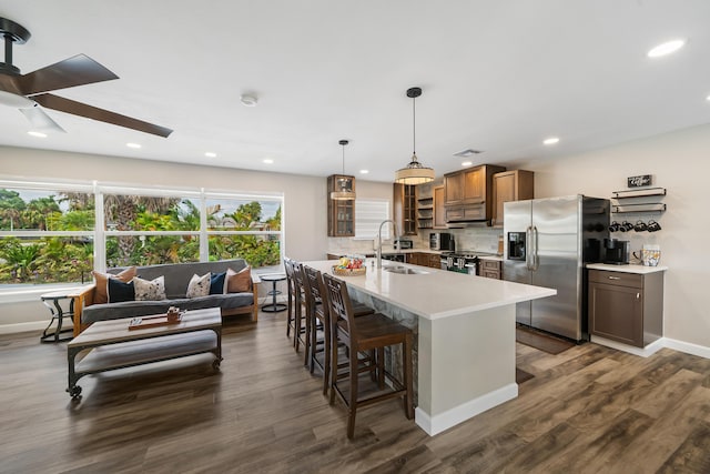 kitchen with appliances with stainless steel finishes, a sink, a breakfast bar, light countertops, and ceiling fan