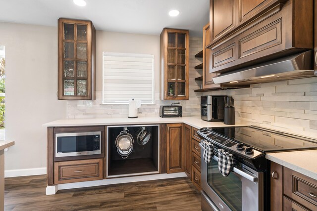 kitchen featuring appliances with stainless steel finishes, recessed lighting, backsplash, light countertops, and glass insert cabinets