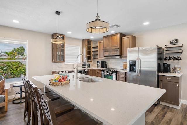 kitchen with a sink, appliances with stainless steel finishes, backsplash, dark wood-style floors, and glass insert cabinets