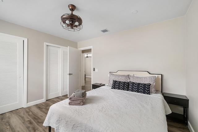 bedroom featuring wood finished floors, baseboards, and multiple closets