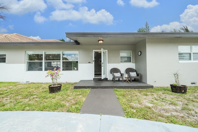 property entrance featuring stucco siding and a yard