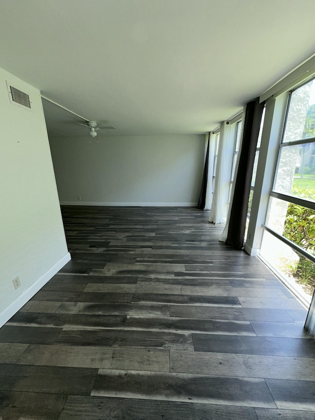851 Three Islands Blvd Unit 102, Hallandale Beach, FL 33009 - empty room featuring dark wood-style floors, baseboards, a ceiling fan, and expansive windows