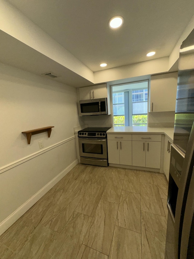 851 Three Islands Blvd Unit 102, Hallandale Beach, FL 33009 - kitchen with appliances with stainless steel finishes, light countertops, white cabinetry, baseboards, and light marble finish floors