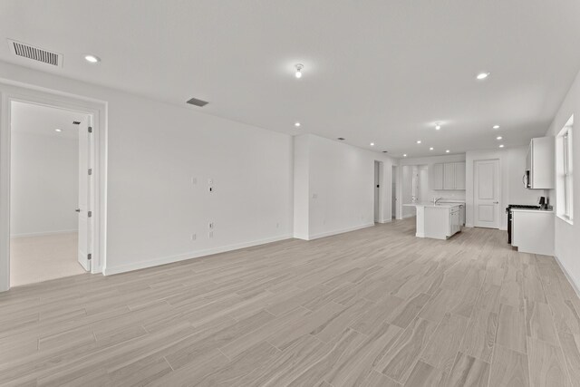 13461 SW Bally Dr, Port Saint Lucie, FL 34987 - unfurnished living room featuring light wood finished floors, recessed lighting, and baseboards