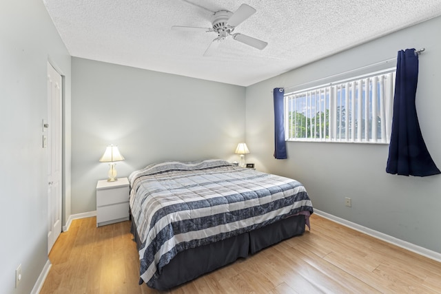 bedroom featuring wood finished floors, a textured ceiling, baseboards, and ceiling fan
