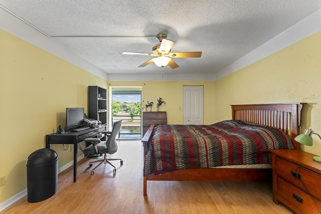 bedroom with wood finished floors, a textured ceiling, access to exterior, an office area, and a ceiling fan