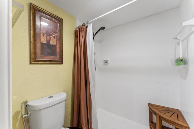 bathroom with a tile shower and toilet