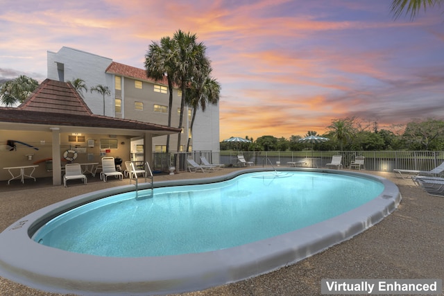 pool at dusk with fence, a community pool, and a patio