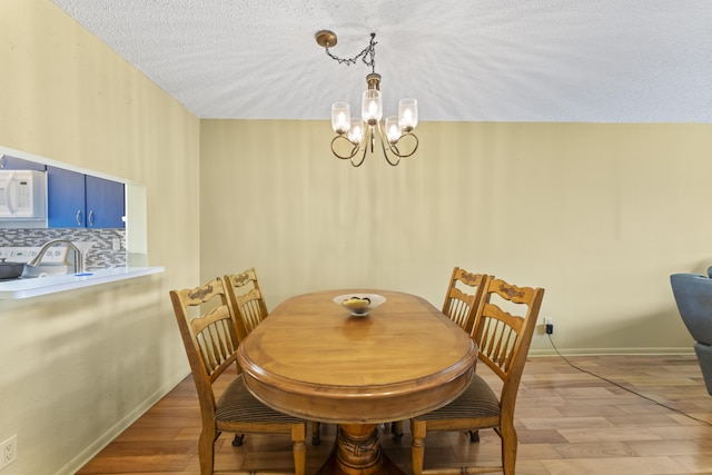 dining area with a chandelier, light wood-type flooring, and baseboards
