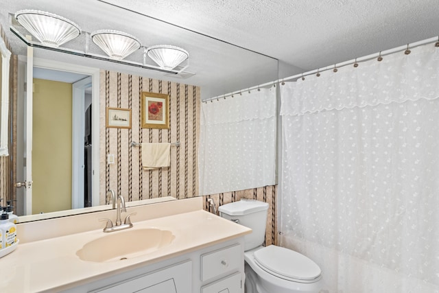 full bathroom featuring wallpapered walls, toilet, vanity, and a textured ceiling