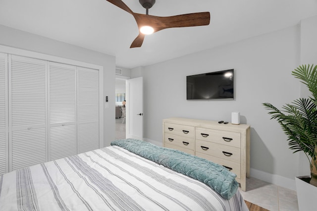 bedroom featuring a closet, baseboards, a ceiling fan, and light tile patterned floors