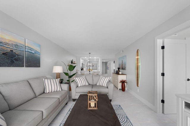 living area featuring light tile patterned flooring, a chandelier, and baseboards