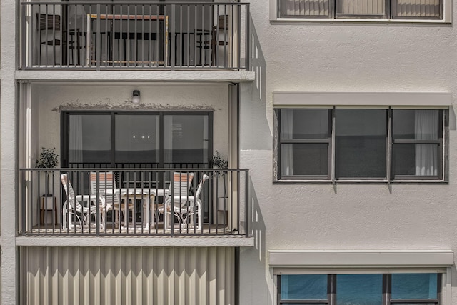 property entrance with a balcony and stucco siding