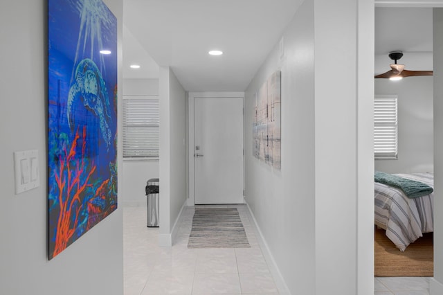 hallway featuring recessed lighting, light tile patterned floors, and baseboards