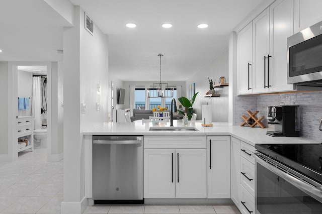 kitchen featuring stainless steel appliances, a sink, light countertops, decorative backsplash, and white cabinetry