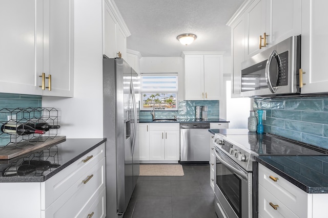 1536 SE 15th Ct Unit 107, Deerfield Beach, FL 33441 - kitchen with stainless steel appliances, backsplash, white cabinets, a sink, and dark tile patterned flooring