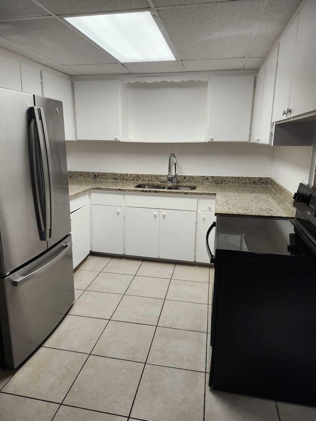 119 S Price St S, Lake Worth, FL 33461 - kitchen featuring freestanding refrigerator, black range with electric cooktop, a sink, a paneled ceiling, and white cabinets