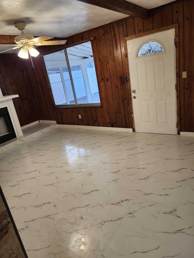 119 S Price St S, Lake Worth, FL 33461 - foyer entrance featuring wooden walls, marble look tiles, a glass covered fireplace, and a ceiling fan