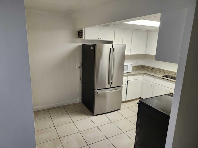 119 S Price St S, Lake Worth, FL 33461 - kitchen with freestanding refrigerator, white microwave, black range with electric cooktop, and white cabinetry