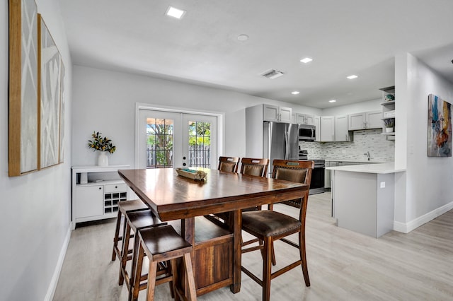 dining room with french doors, light wood-style floors, baseboards, and recessed lighting