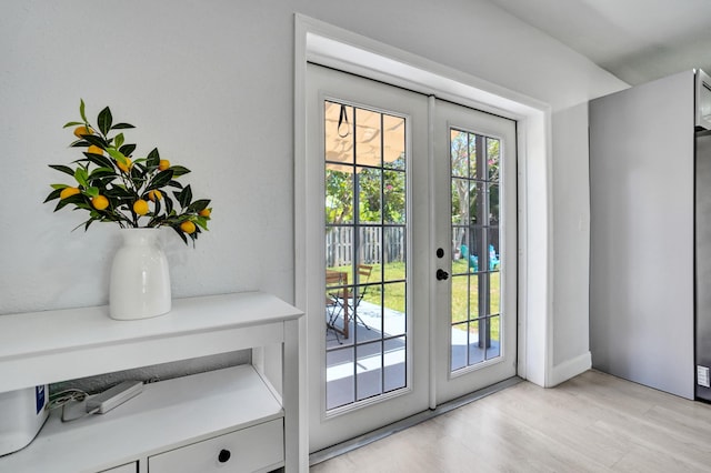 entryway with light wood-style floors, french doors, and baseboards