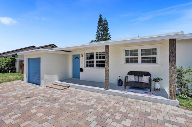 view of front of home with stucco siding, an attached garage, and decorative driveway