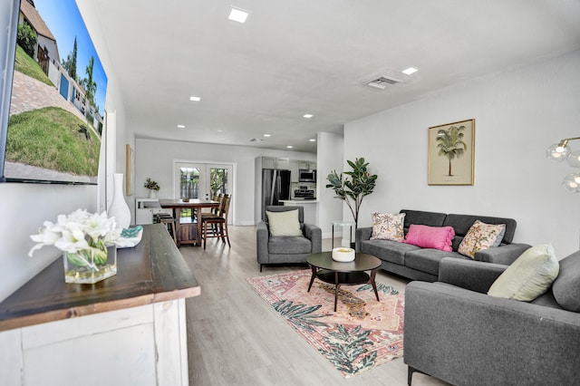 living area featuring light wood-style floors, recessed lighting, and french doors