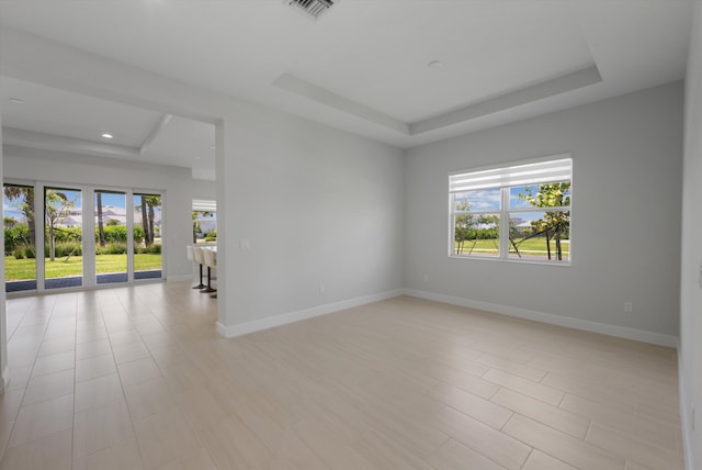 unfurnished room featuring a tray ceiling, plenty of natural light, baseboards, and recessed lighting