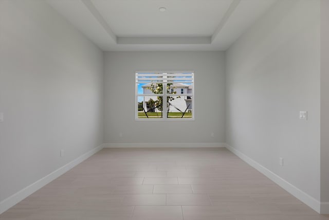 spare room with a tray ceiling and baseboards