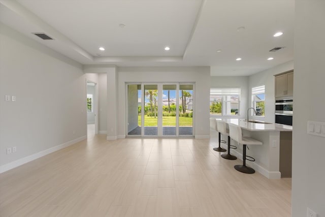 living room featuring baseboards, recessed lighting, and a raised ceiling