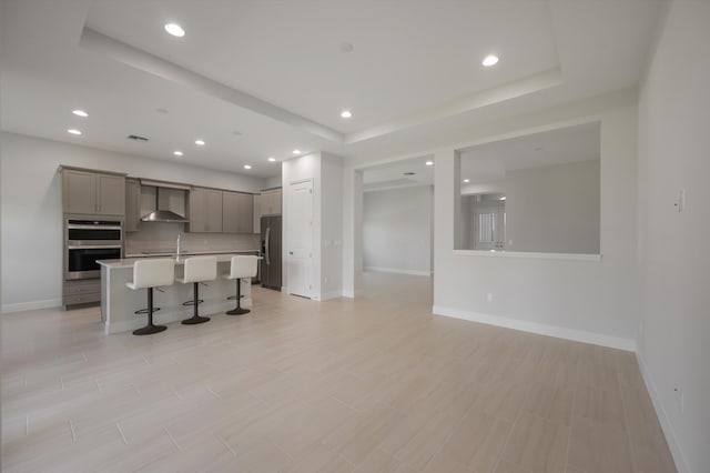 unfurnished living room featuring baseboards, recessed lighting, a raised ceiling, and a sink