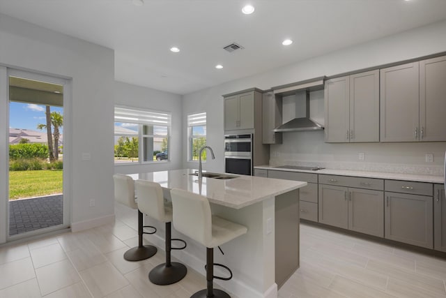 kitchen featuring gray cabinets, wall chimney exhaust hood, a sink, stainless steel double oven, and black electric cooktop