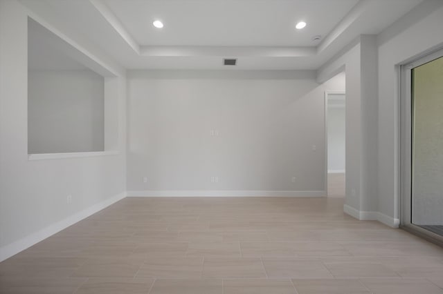 unfurnished room featuring a tray ceiling, recessed lighting, and baseboards