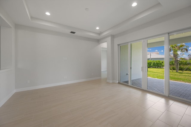 unfurnished room with a tray ceiling, recessed lighting, and baseboards