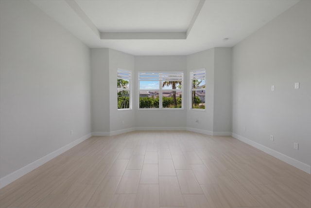 spare room with a tray ceiling and baseboards