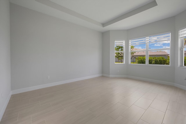 unfurnished room featuring a tray ceiling and baseboards