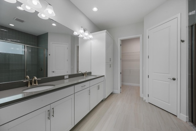 bathroom featuring a stall shower, double vanity, a spacious closet, baseboards, and recessed lighting