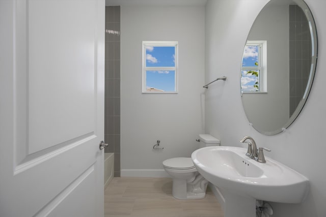 full bath with toilet, baseboards, a sink, and shower / bathtub combination