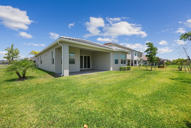 back of property with stucco siding, a yard, and a patio