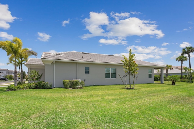 view of side of property featuring a lawn, stucco siding, and a tiled roof